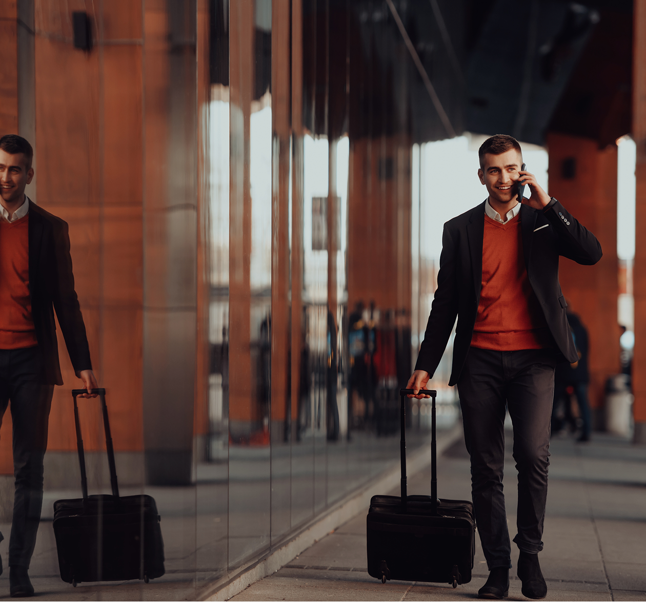 A man in a coat and tie is pulling a suitcase, suggesting he is traveling or heading to a formal event.